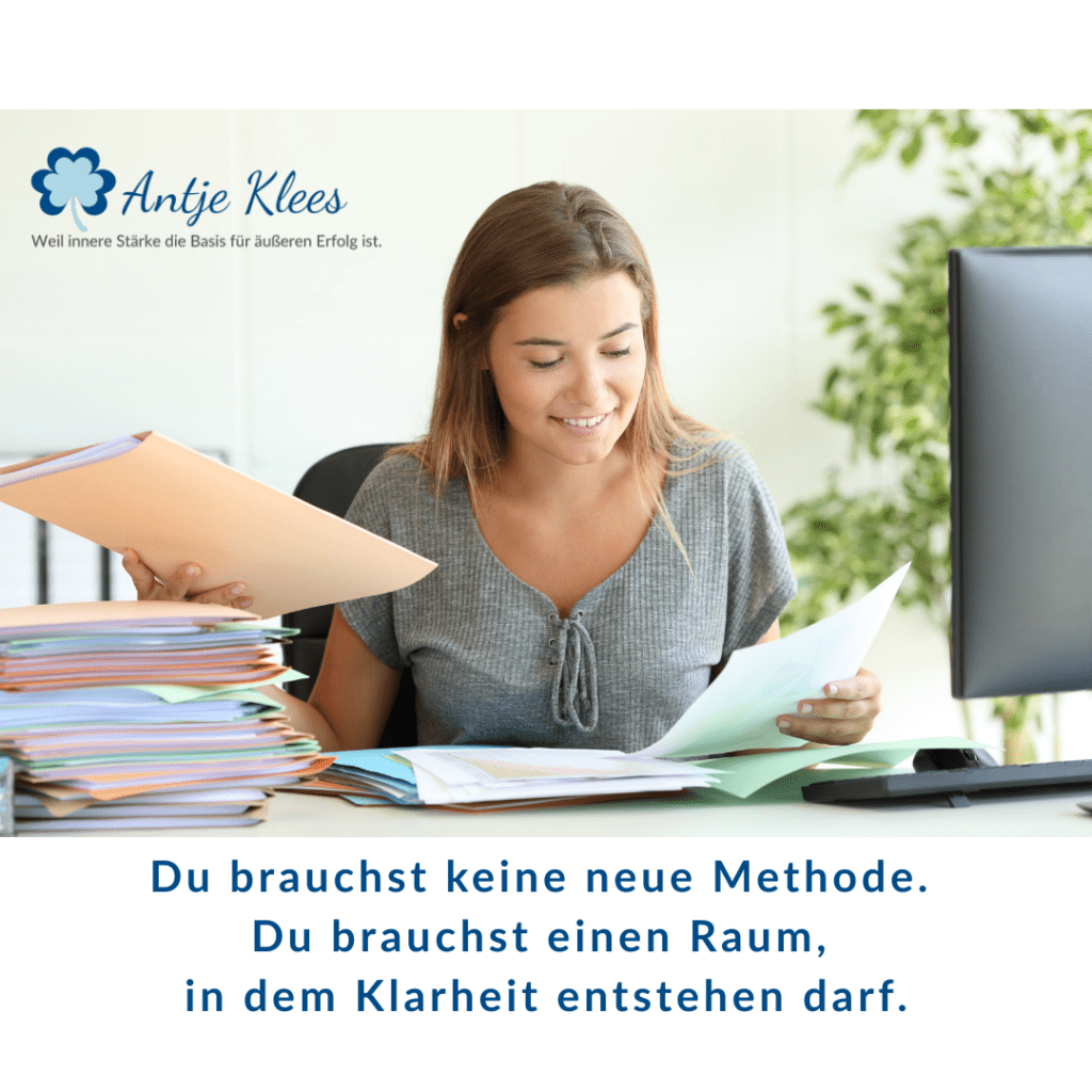 Raum_fuer_Klarheit Eine Mitarbeiterin sitzt an ihrem Schreibtisch und schaut eine Akte durch.