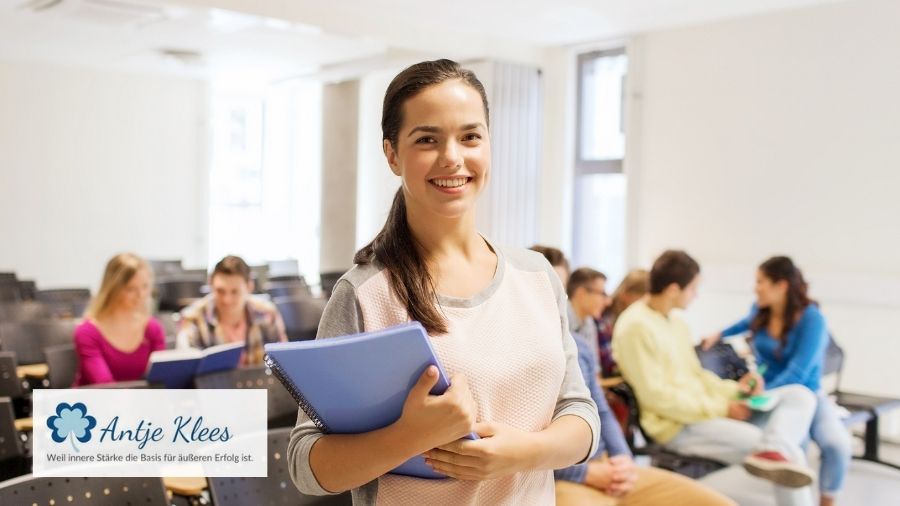 Eine Hochschullehrende steht glücklich und zufrieden in einem Hörsaal